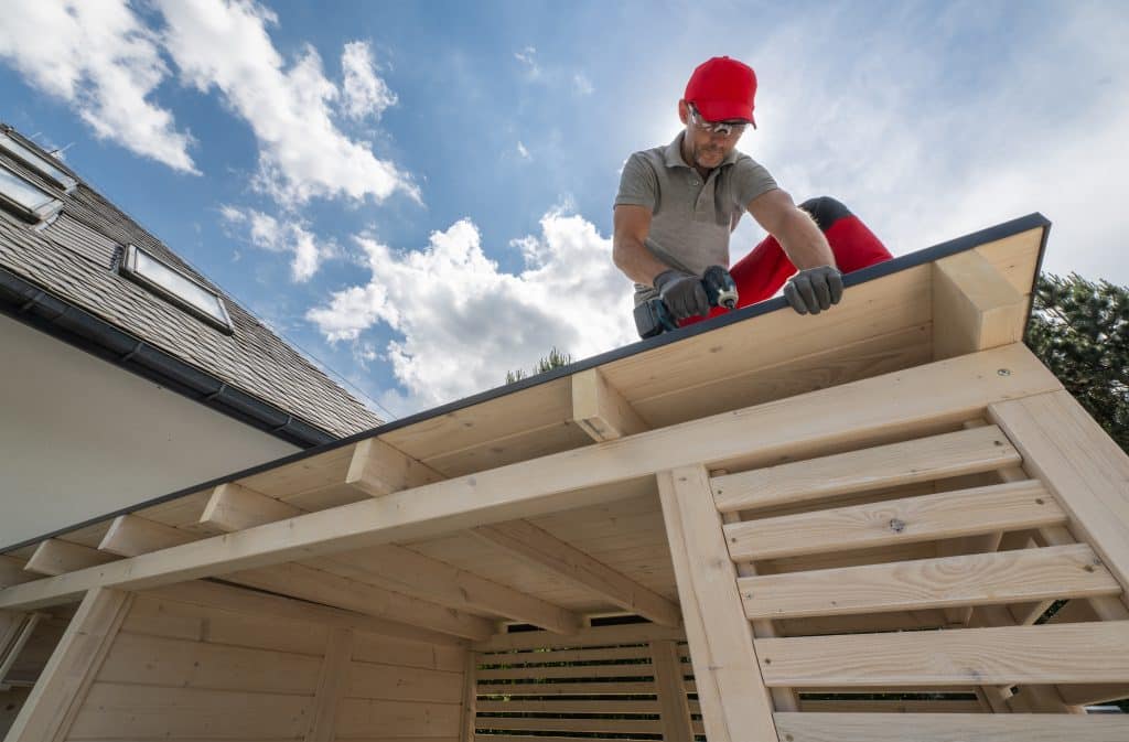 man installing roof on wooden structure